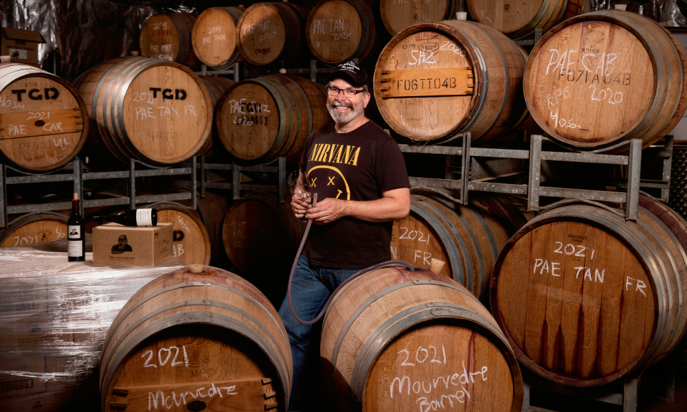 Winemaker surrounded by wooden wine barrels 